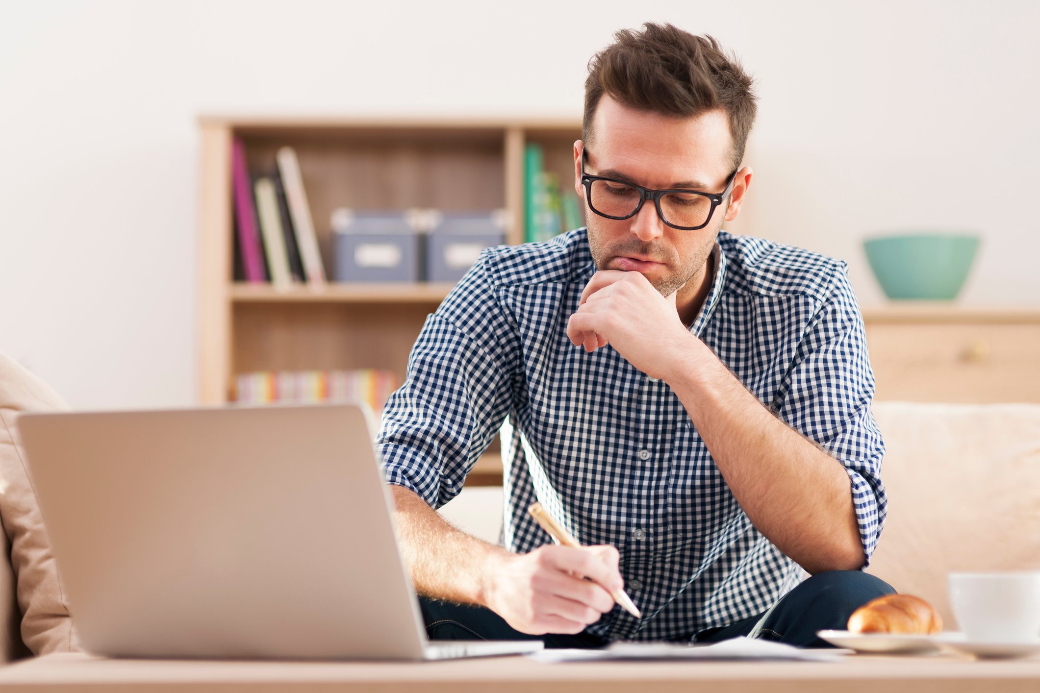 Man holding pen in front of laptop