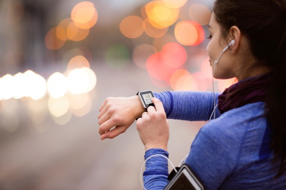 A young woman selects music on her smart watch.