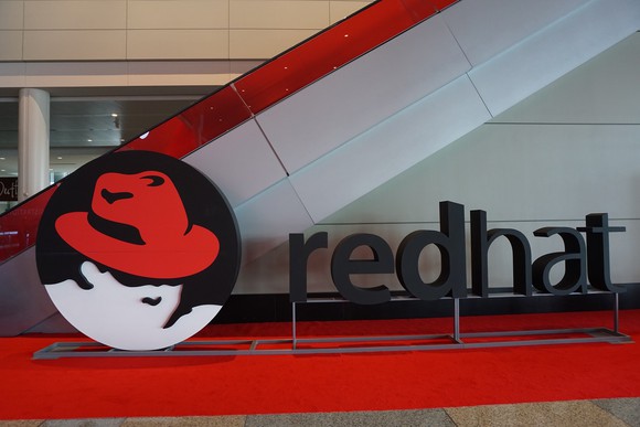 Red Hat logo in front of a staircase going up.