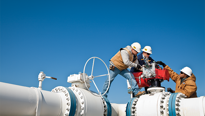 Three pipeline workers maintaining a pipeline