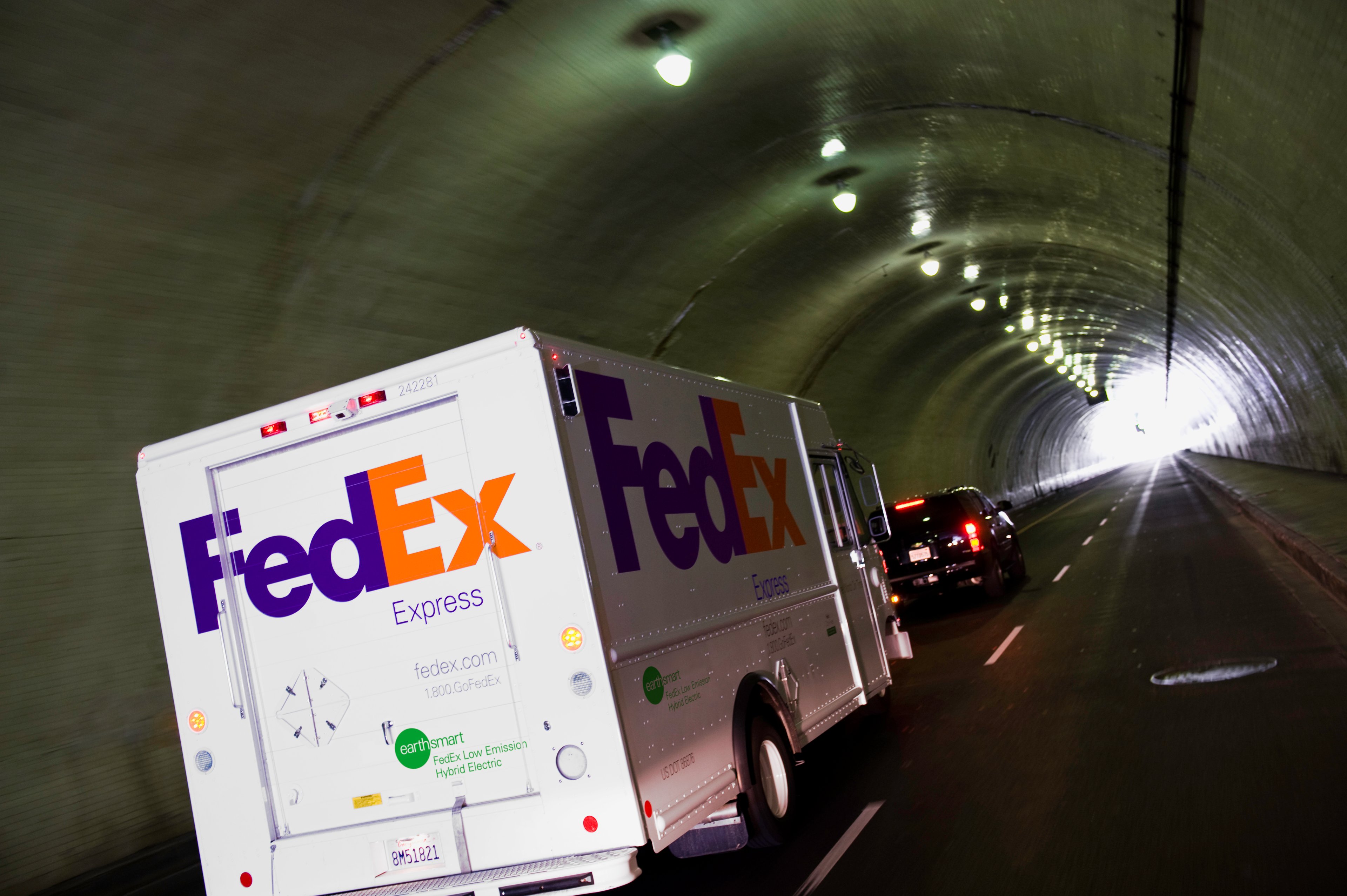 A FedEx hybrid truck driving through a tunnel.