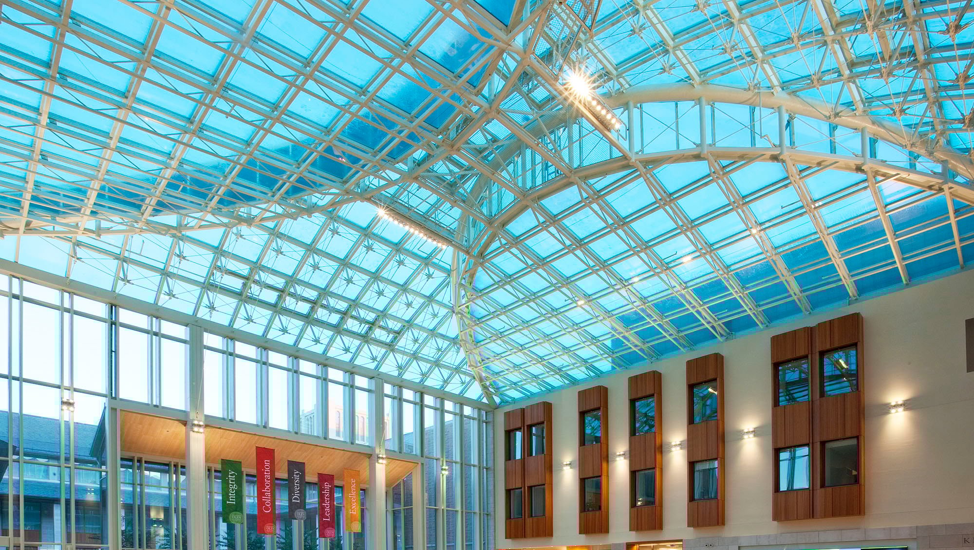 Blue glass ceiling with metal framing over a wide-open lobby space.