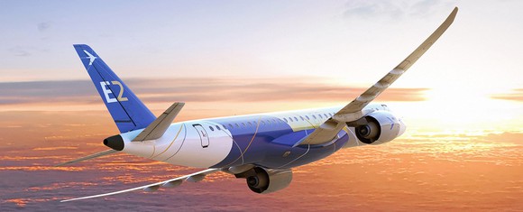 Embraer E2 jet, airborne flying toard a rising or setting sun with few clouds below.