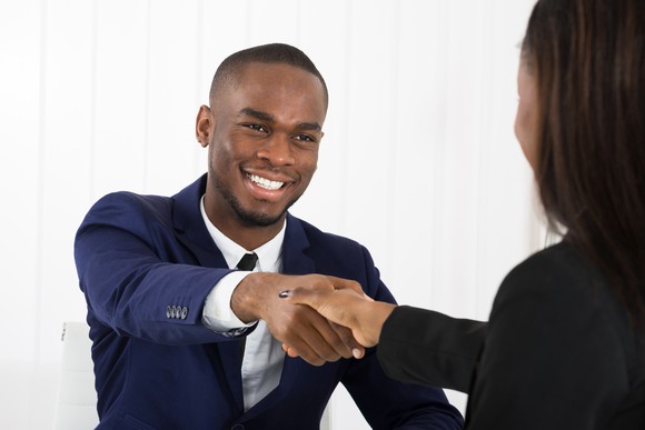 Man in suit shaking hands with professionally dressed woman