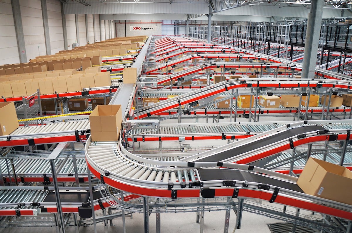 Boxes move on a series of conveyor belts inside a warehouse.