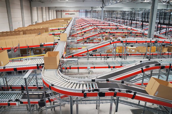 Boxes move on a series of conveyor belts inside a warehouse.