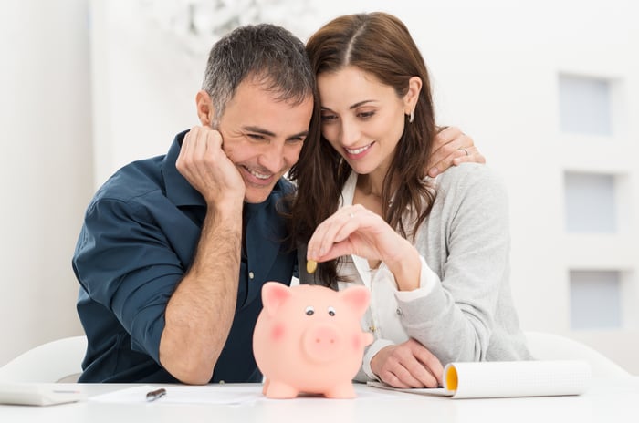 A couple putting coins in their piggy bank.