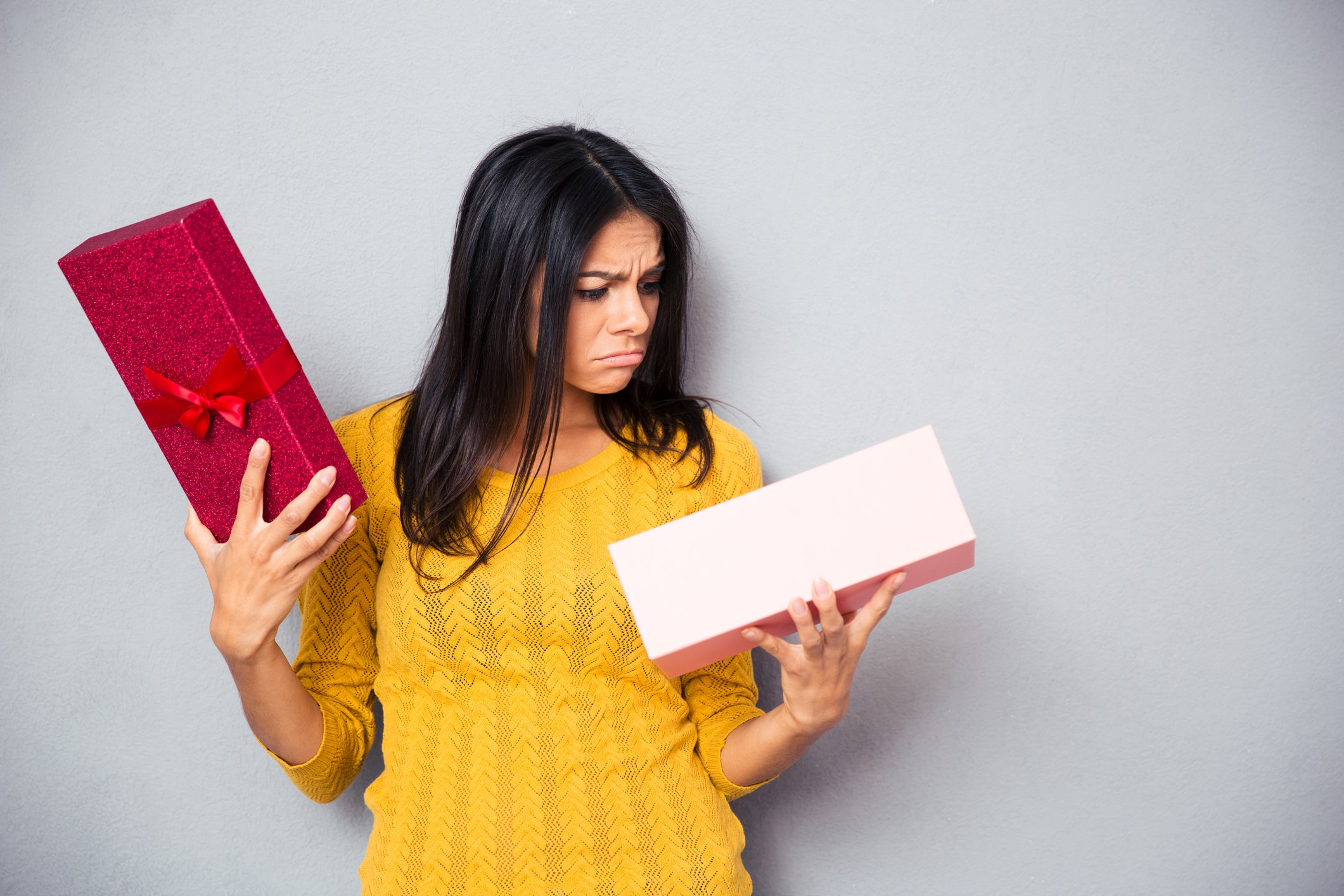 A woman opens a gift box and has a look of disgust on her face.