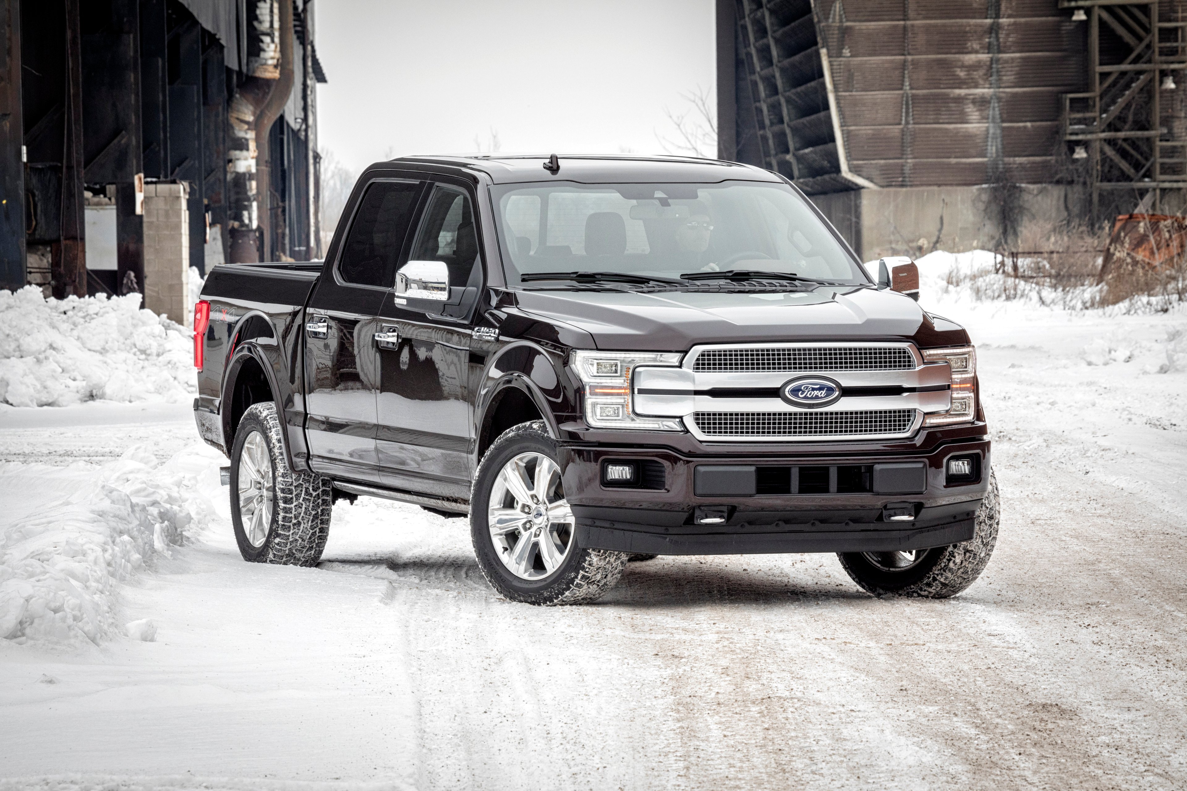 A black 2018 Ford F-150 pickup truck on a snowy street. 