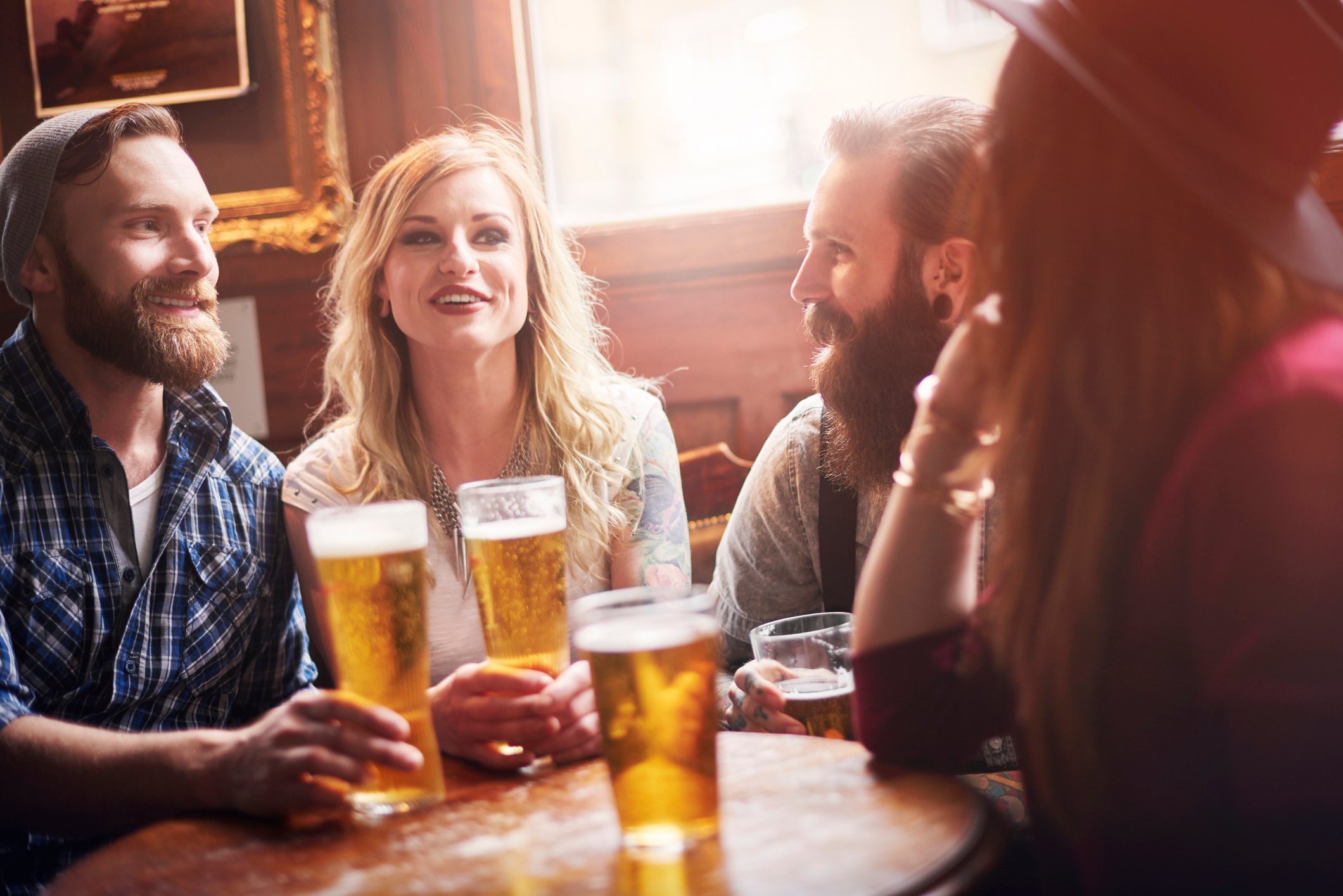 Four friends drinking beer at a bar.