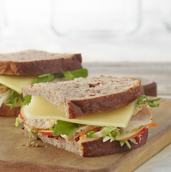 A turkey, apple, and cheddar sandwich from Panera, displayed on a wood cutting board.