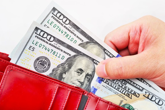 Picking two hundred-dollar bills out of a red wallet.