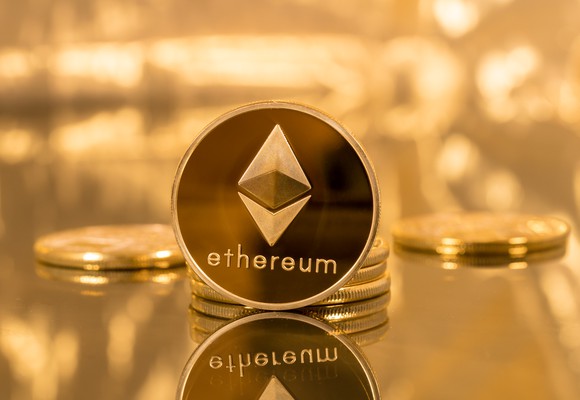 A gold-and-dark colored coin with "ethereum" on it, in front of a golden background.