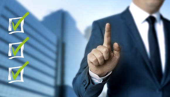 Businessman holding index finger up next to three checkboxes