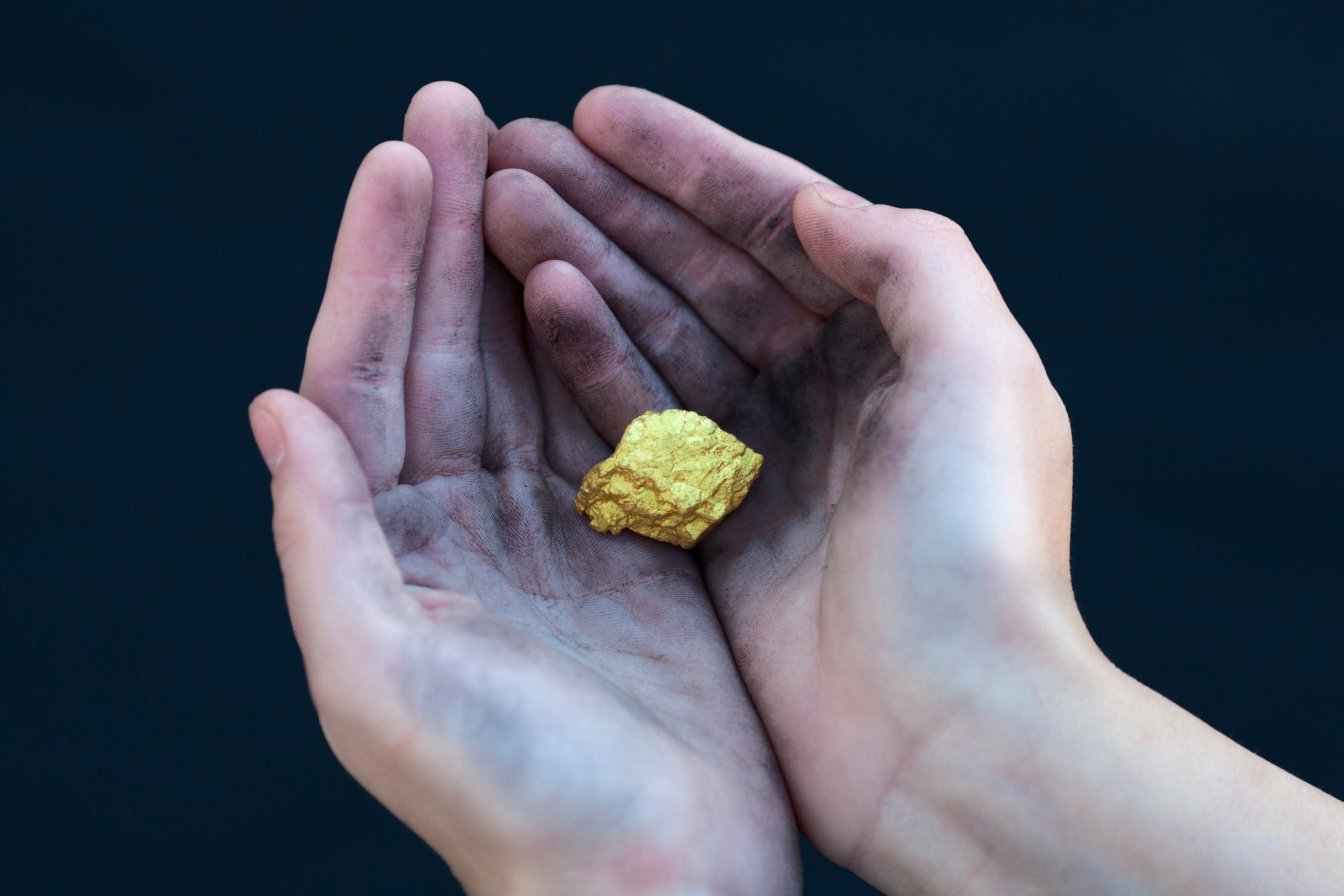 Two hands cradle a gold nugget.