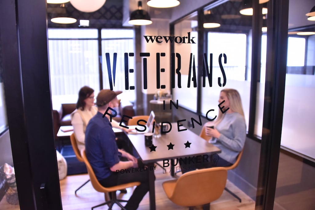 A group of people meeting in a room labeled "WeWork Veterans in Residence"