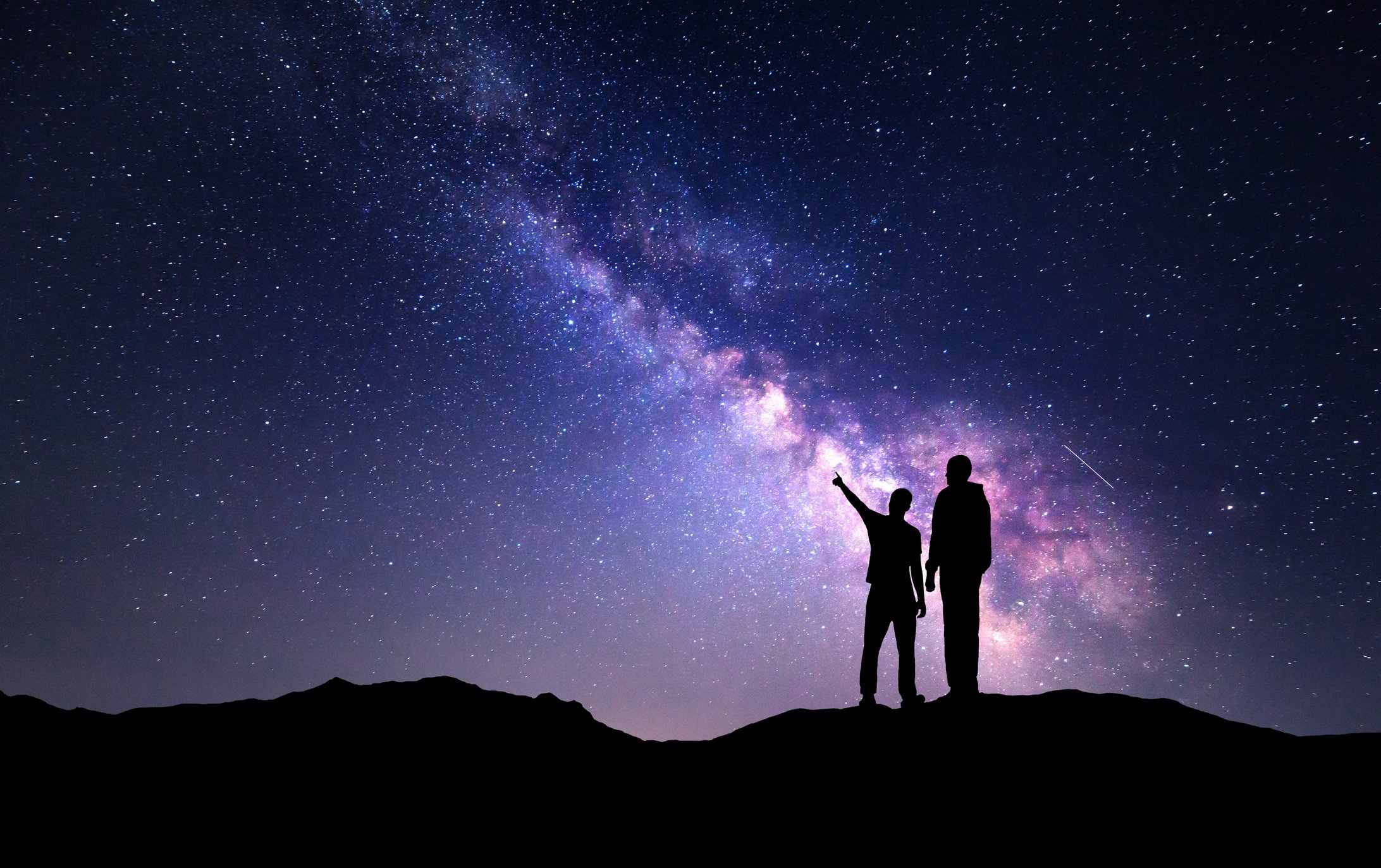 Father and son gazing at the Milky Way galaxy