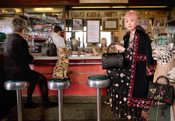 A woman holding a Kate Spade handbag while sitting at the counter in a diner. 