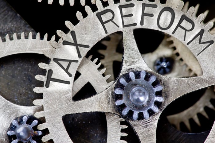 Metal clockwork gears laced together, with Tax Reform carved on one.