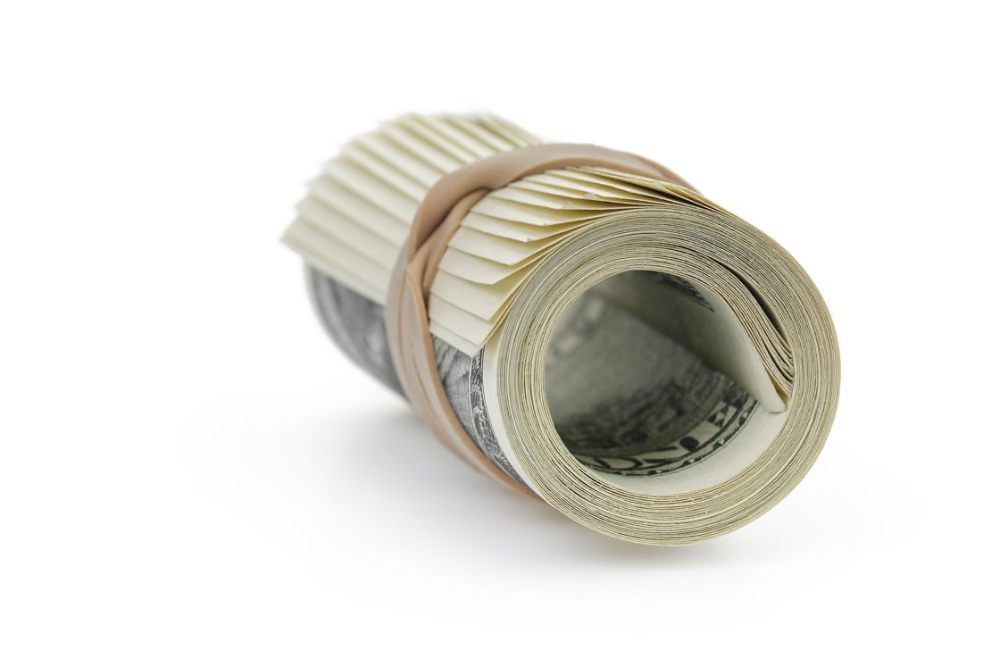 A roll of U.S. currency held together with a rubber band.