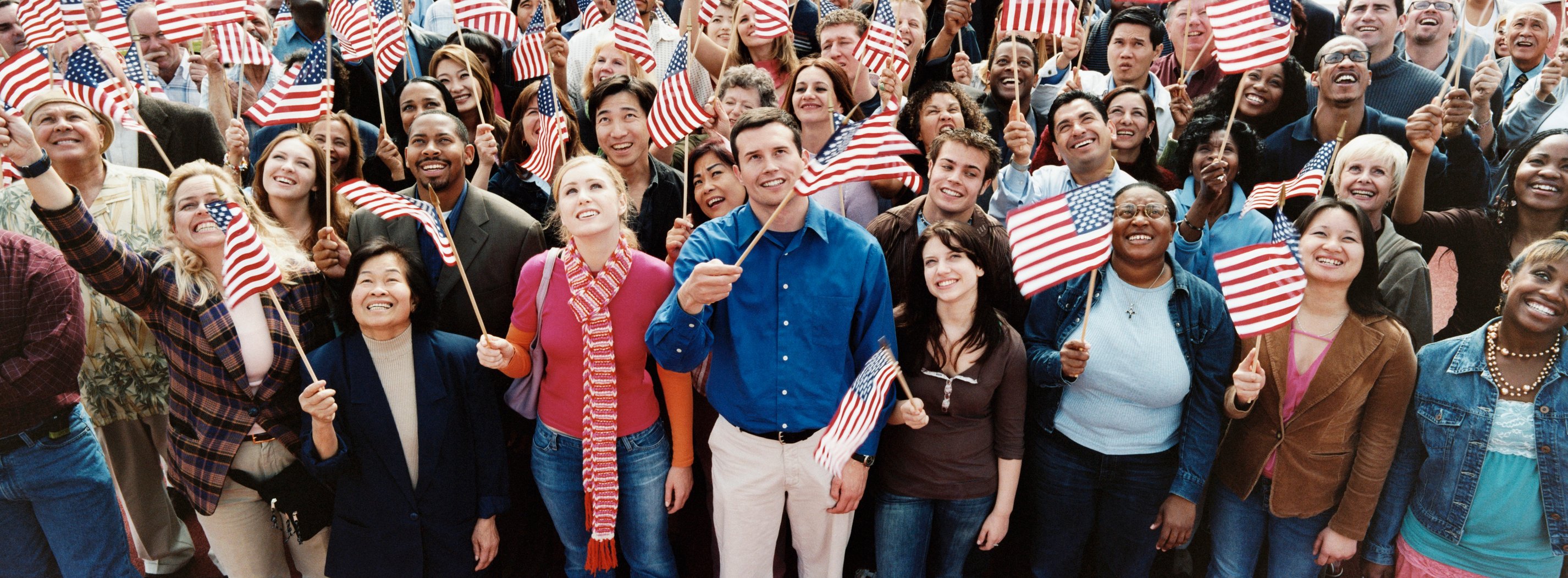Dozens of people holding U.S. flags at a group gathering.