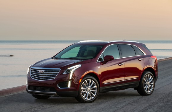 A dark red 2018 Cadillac XT5, a midsize crossover SUV, parked on a beach.