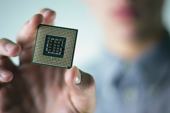 A hand holding what looks like an Intel microprocessor