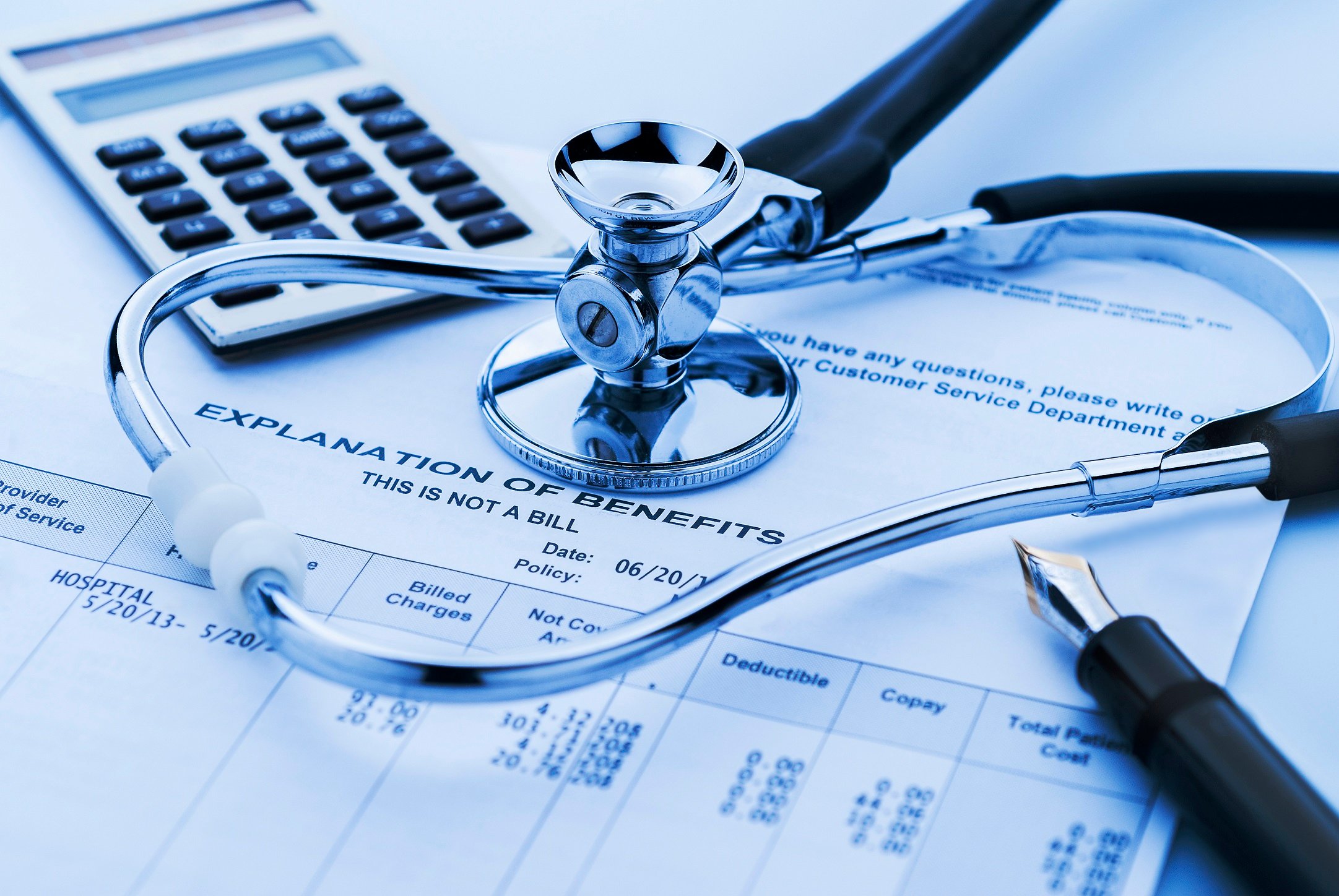 Health insurance benefits form with stethoscope, calculator, and pen on top.