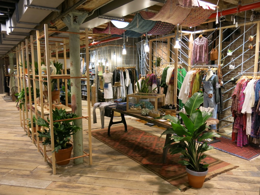 A scene inside an Urban Outfitters store where clothing and plants are displayed.