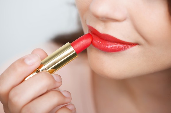 A woman applying red lipstick.