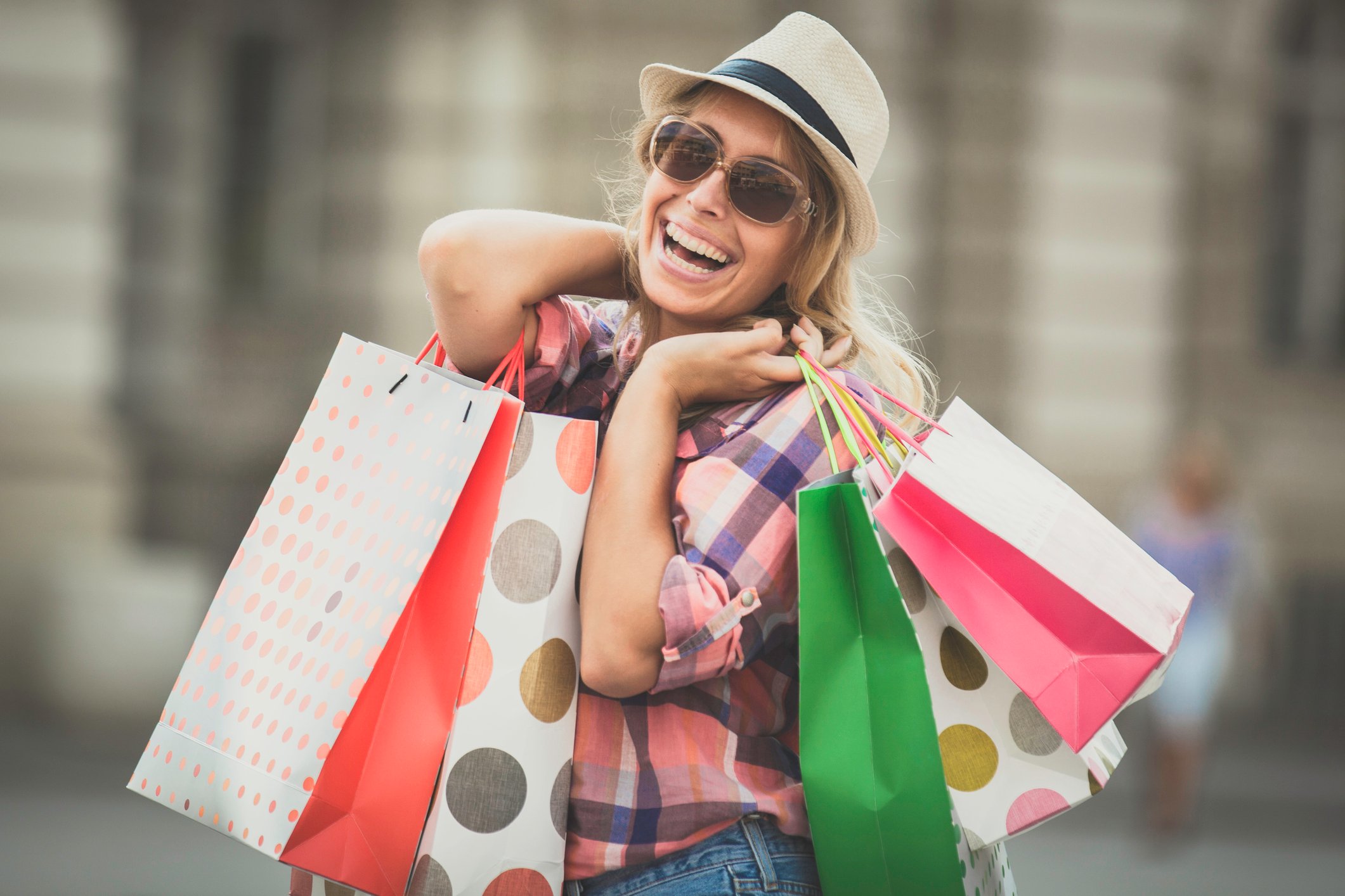 A smiling woman holds several shopping bags.