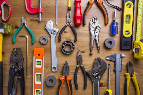 A wide variety of hand-held tools on a table.