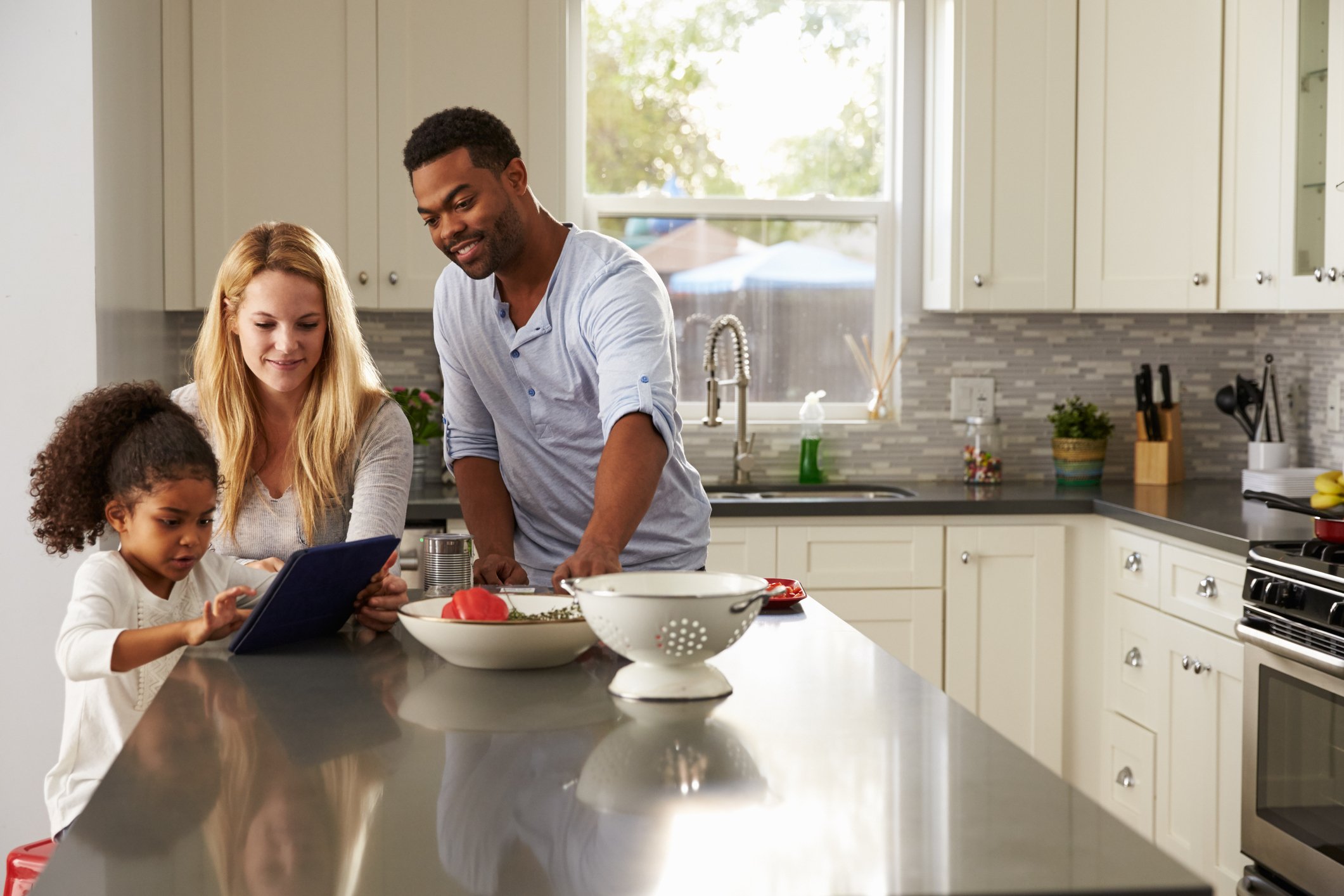 Family sitting in kitchen using a tablet.
