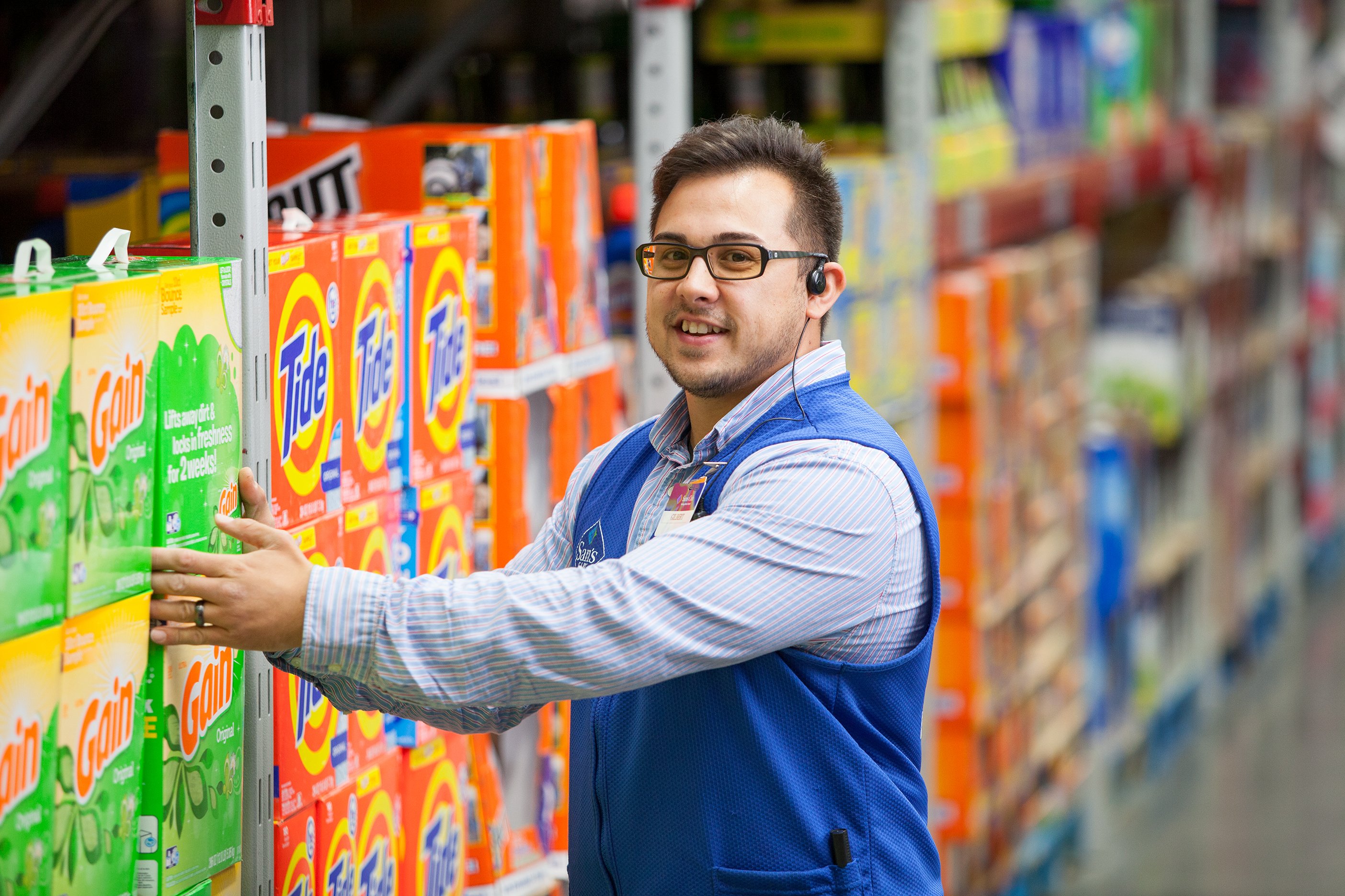A Sam's Club employee stacking boxed detergent in a store