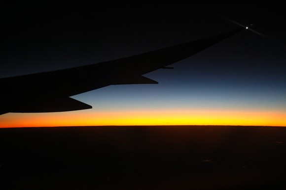 The wing of a Boeing Dreamliner in flight, silhouetted against the night sky.