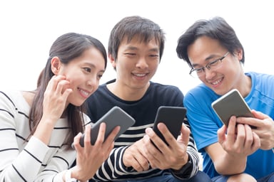 3 people looking at each others smartphones.