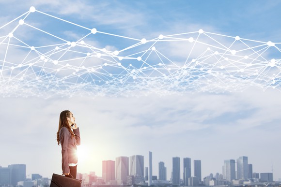 Businesswoman gazes at a city skyline with a web of white lines interconnected above.