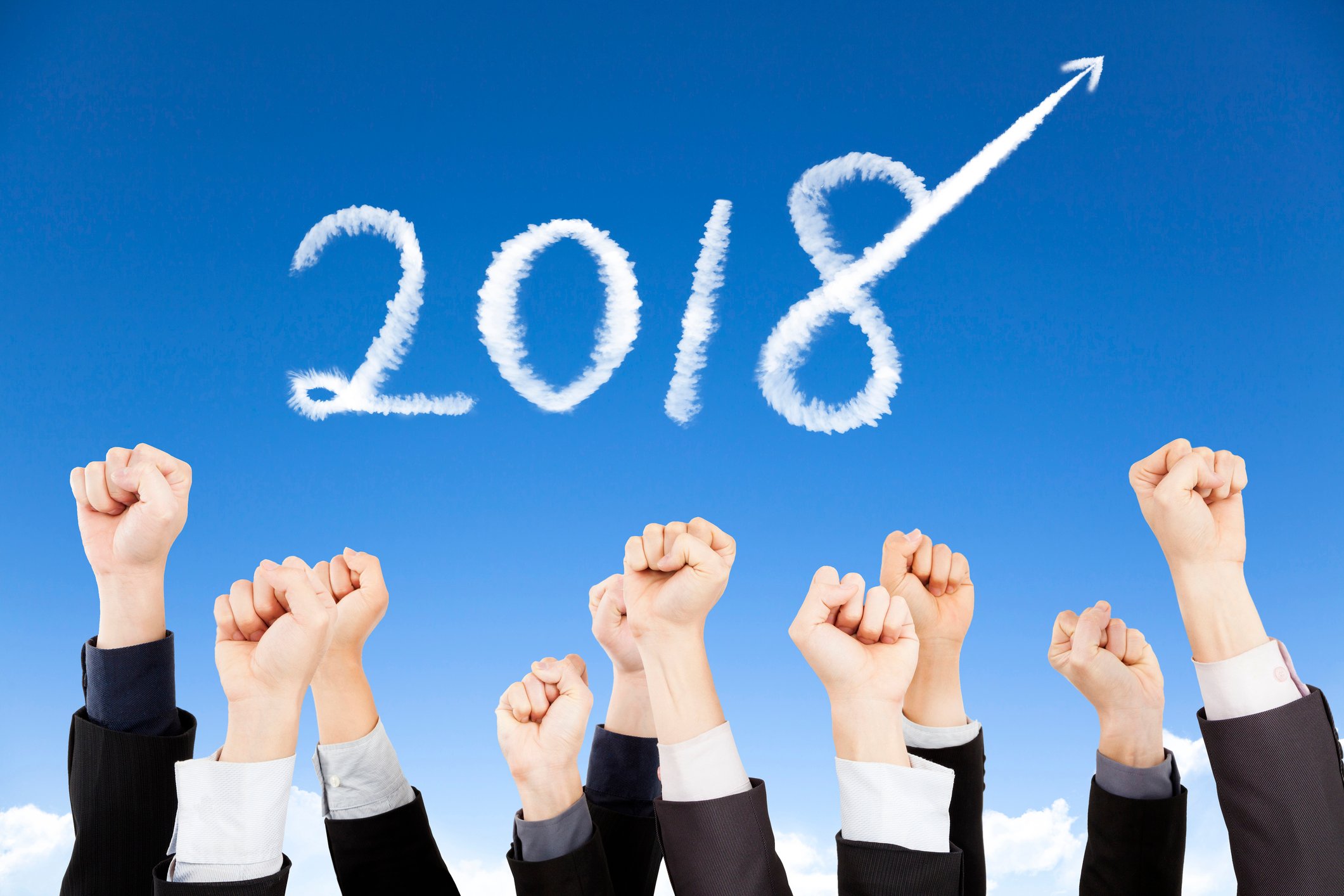 Skywriting of 2018 with several raised fists in the foreground.