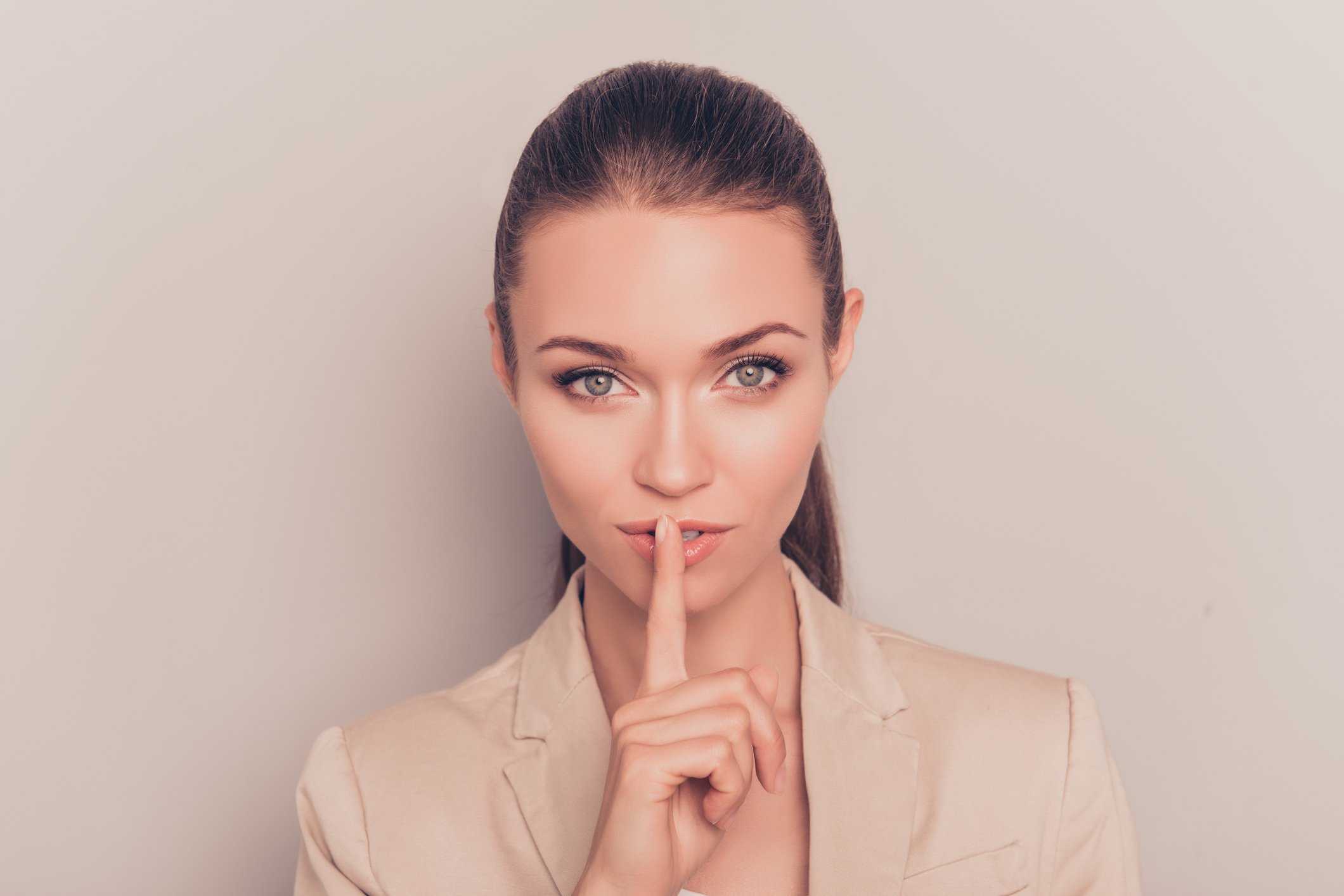 A businesswoman holding her finger to her lips.