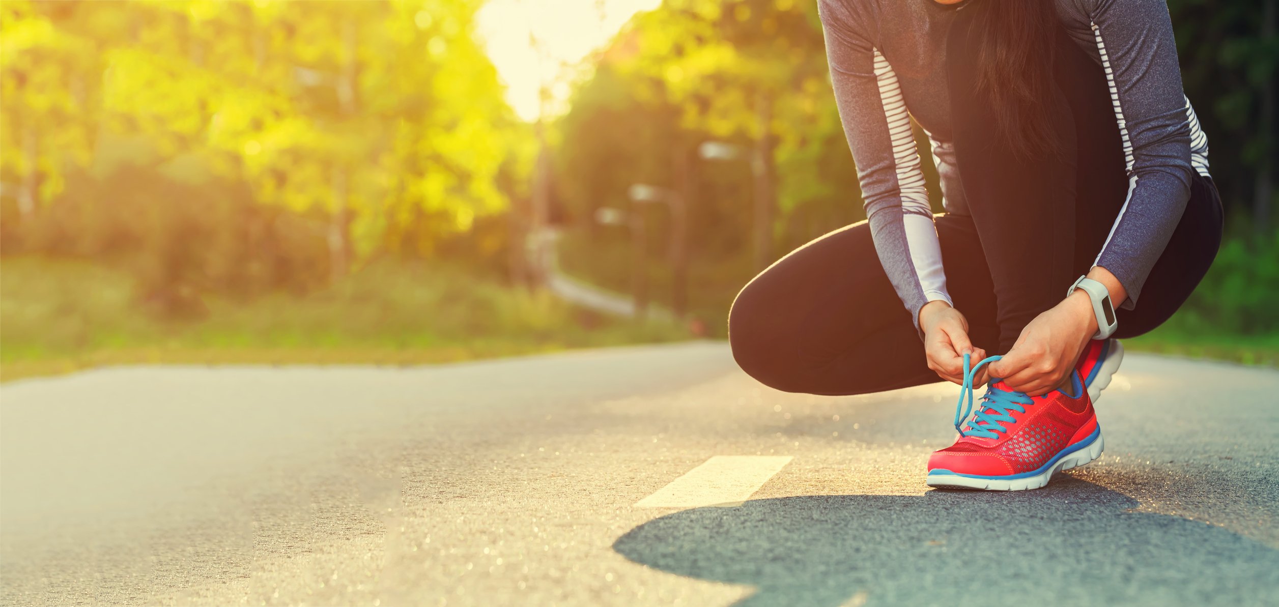 Woman tying her shoe on a road