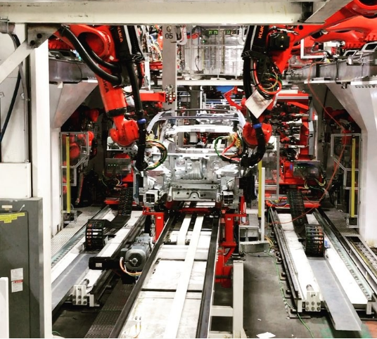 Model 3 production line, showing red robotic arms on both sides of an assembly line. 