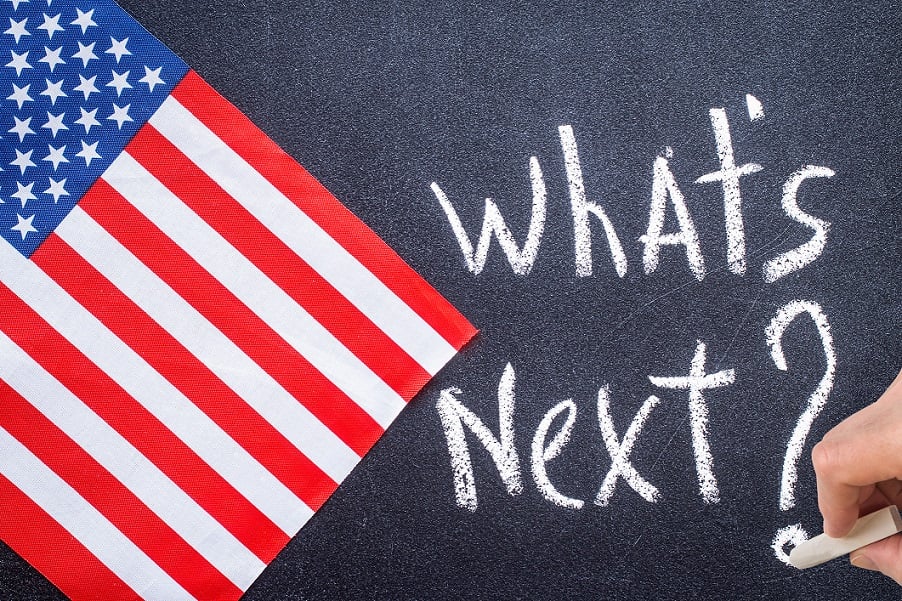 What's Next? written on chalkboard next to an American flag.