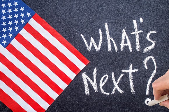 What's Next? written on chalkboard next to an American flag.