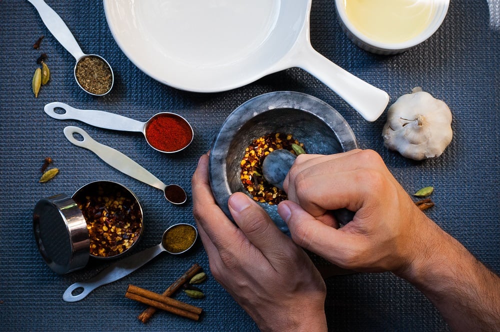 A man using a mortar and pestle to grind spices.