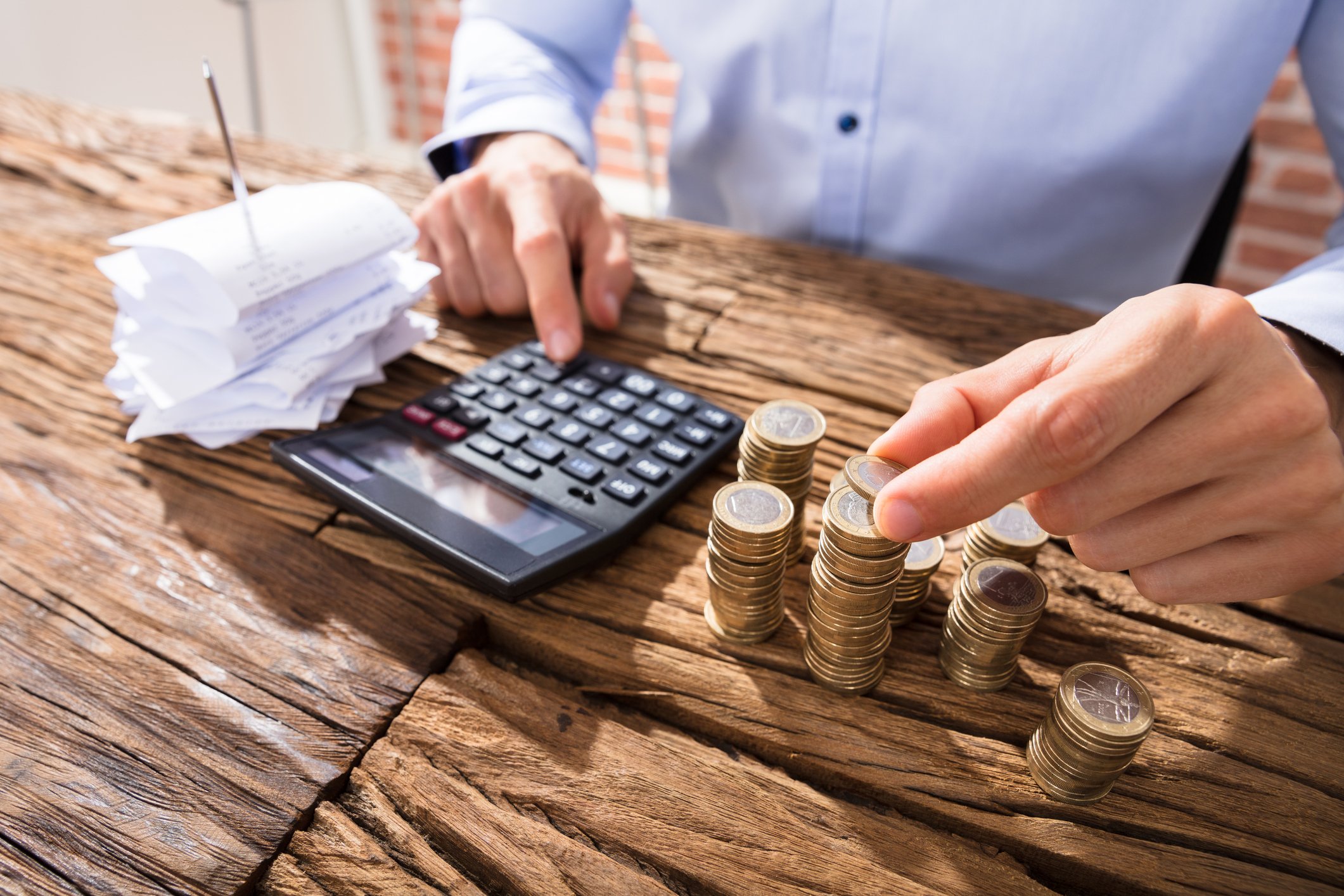 Person counting coins and using a calculator.