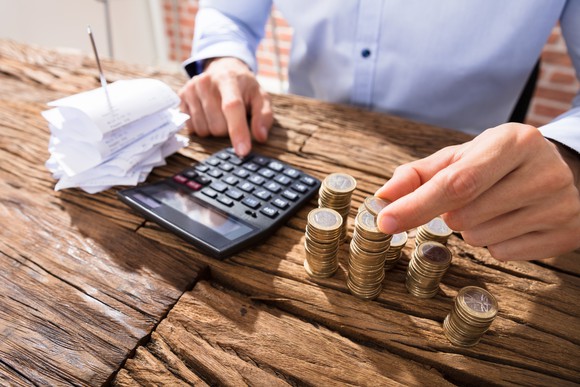 Person counting coins and using a calculator.