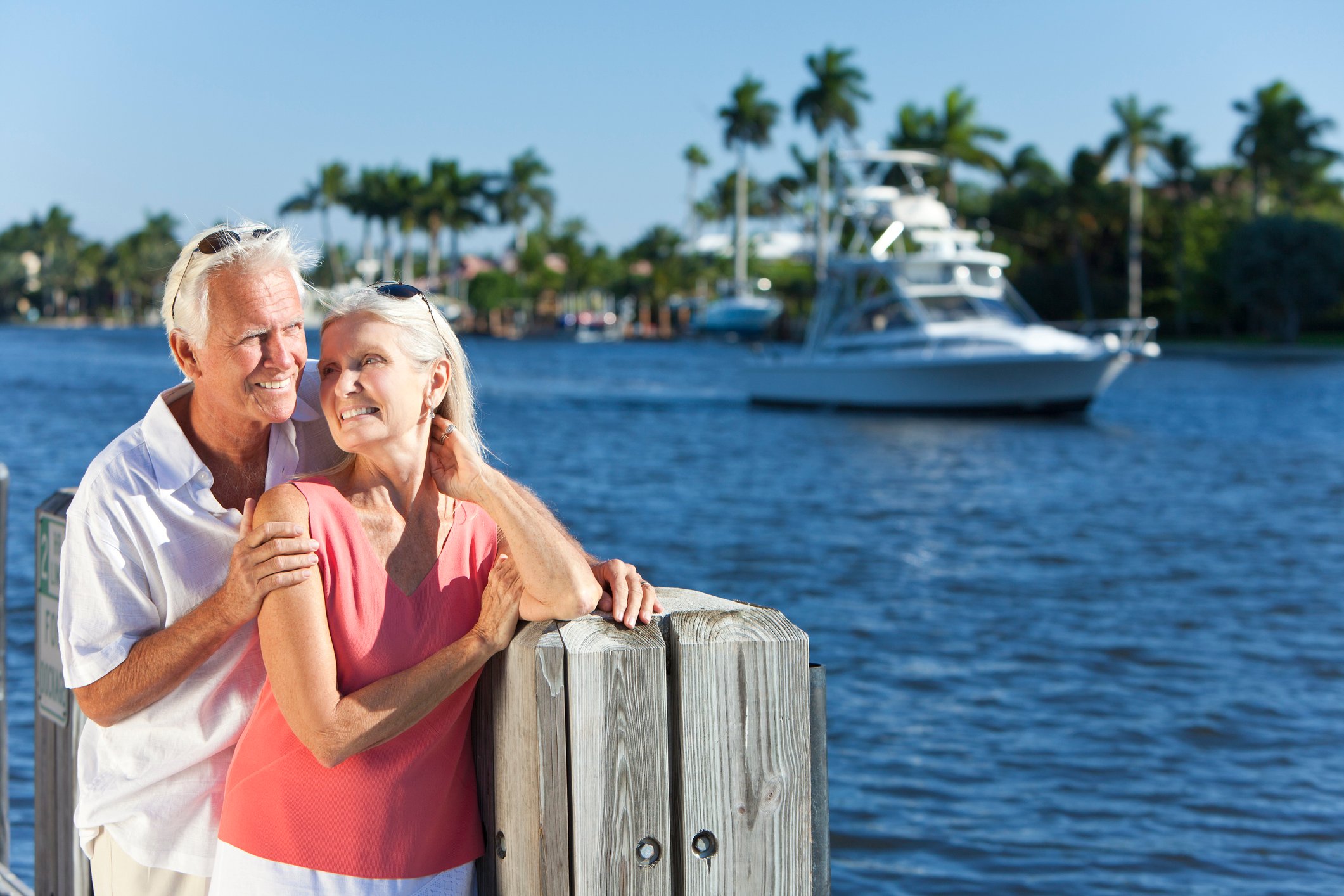 Older couple in front of water with boat in background