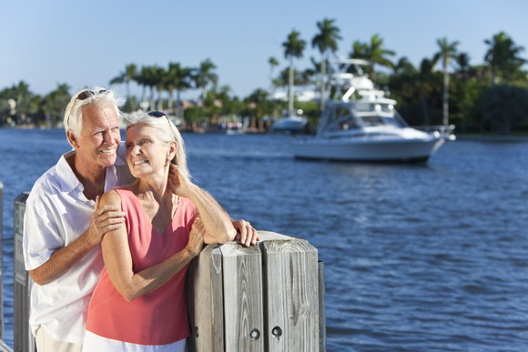 Older couple in front of water with boat in background