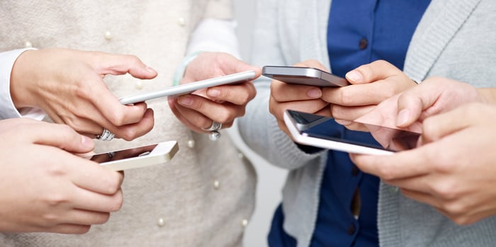 Four people using their smartphones.