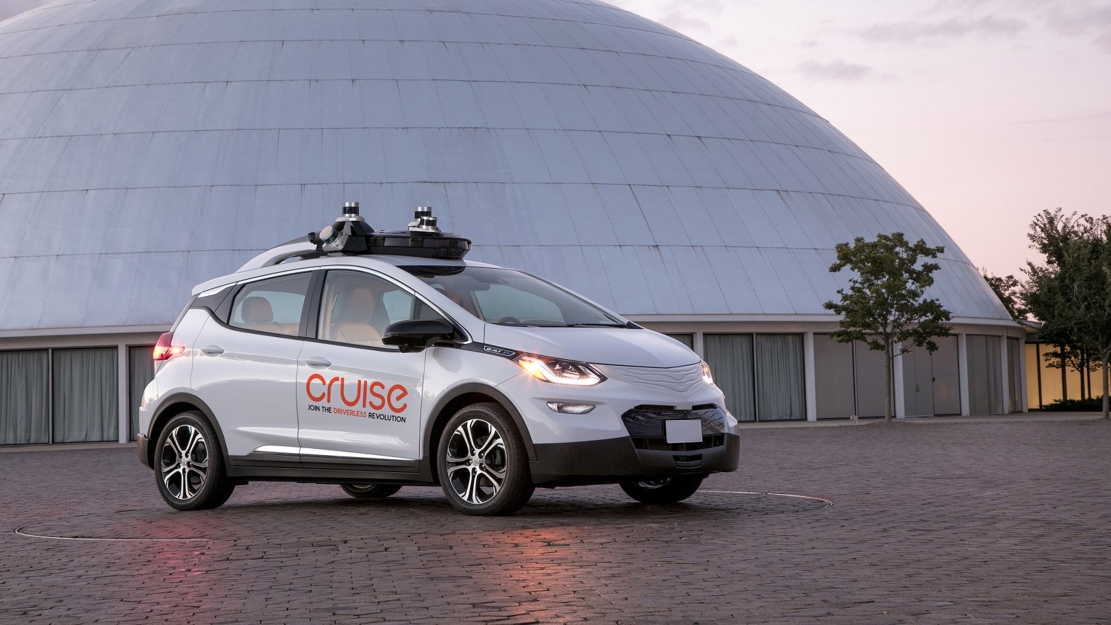 Car sitting on pavement with building in background.